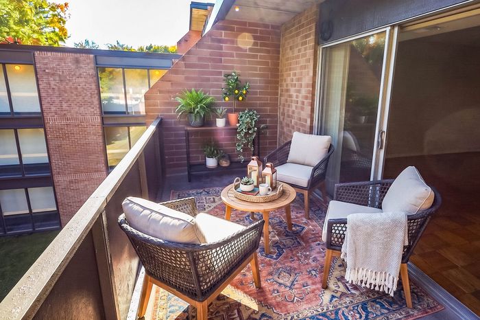 Charming balcony oasis with comfortable seating, lush greenery, and vibrant outdoor rug, perfect for relaxing and entertaining.