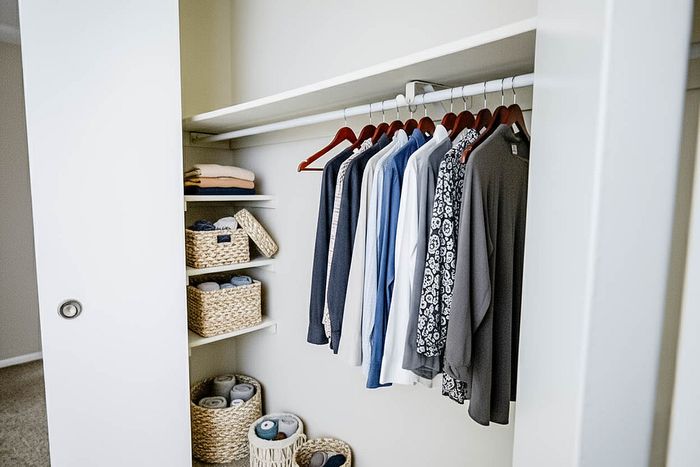 Organized modern closet with stylish storage baskets and neatly hung clothing.