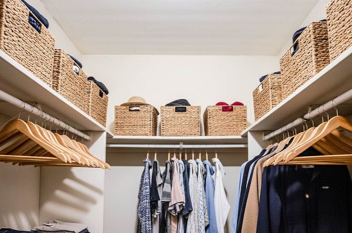 Spacious walk-in closet with woven storage baskets and organized clothes hangers, offering a stylish and functional storage solution.