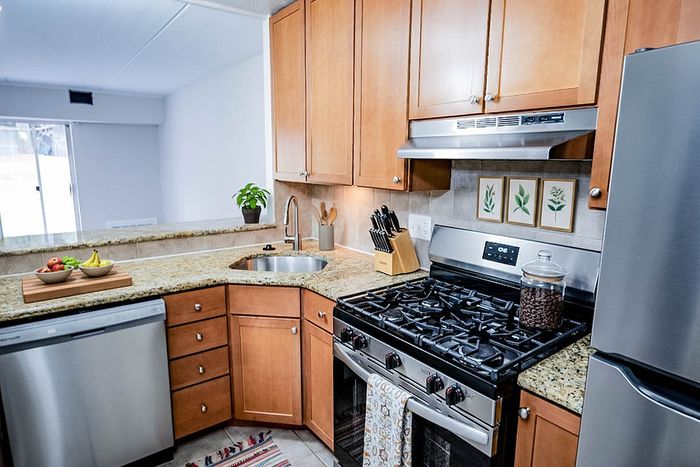 Modern kitchen with sleek stainless steel appliances, granite countertops, and warm wooden cabinetry, perfect for culinary enthusiasts.