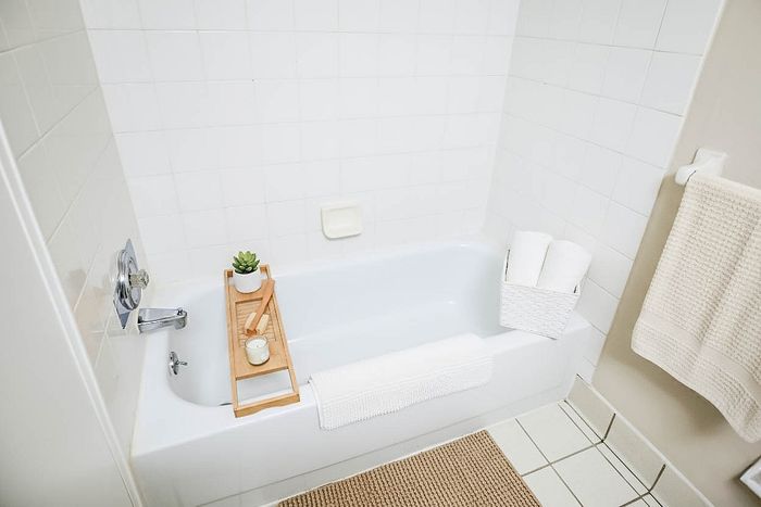 Inviting bathroom with a sleek bathtub, wooden bath tray, and plush towels, exuding a serene spa-like atmosphere.