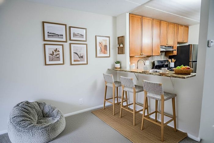 Cozy apartment with a modern kitchen, inviting breakfast bar with elegant stools, and stylish wall art creating a warm atmosphere.