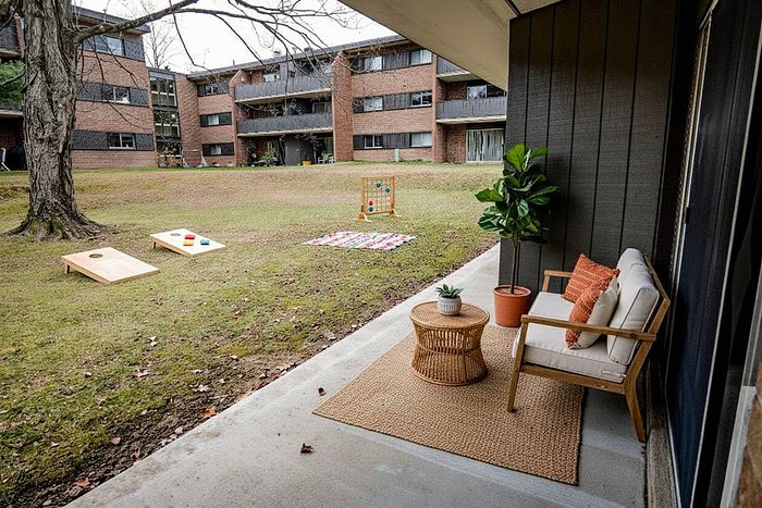 Charming apartment patio with cozy seating, vibrant pillows, and a lively outdoor games area, offering a perfect blend of relaxation and entertainment.