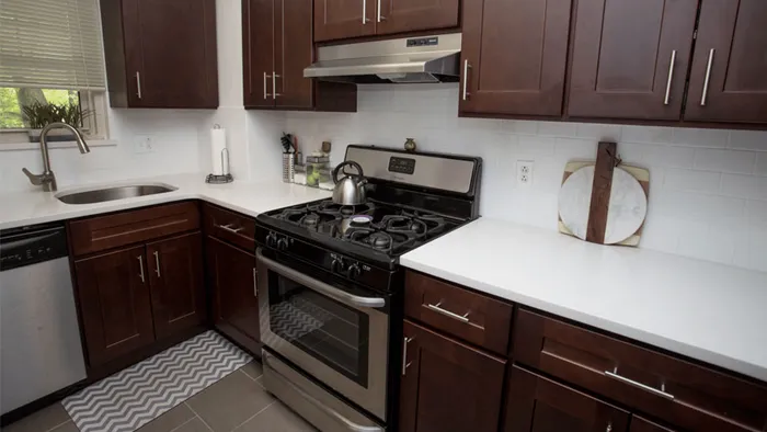 Modern kitchen with sleek dark wood cabinets, stainless steel appliances, and a stylish tile backsplash, creating an inviting cooking space.