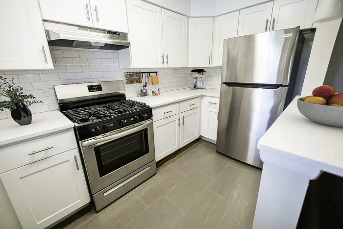 Modern kitchen with sleek stainless steel appliances, chic white cabinetry, and elegant tile backsplash.