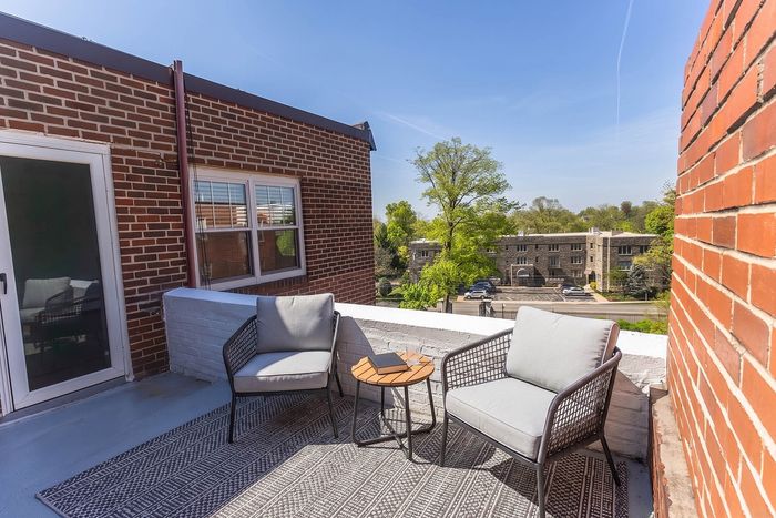 Charming outdoor patio with cozy seating overlooking a vibrant neighborhood street, perfect for relaxation on a sunny day.