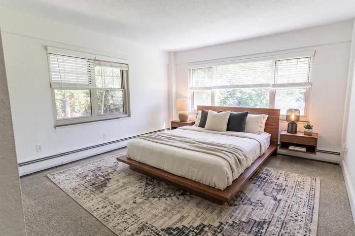 Bright and spacious bedroom featuring a modern wooden bed, large windows with garden views, and elegant decor.