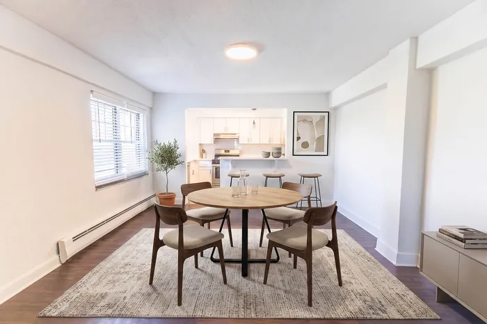 Bright and inviting open-concept dining area with modern wooden furniture and cozy ambiance, featuring a stylish kitchen and large windows.