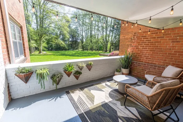 Charming apartment patio with cozy seating, string lights, and lush green views, perfect for relaxation.
