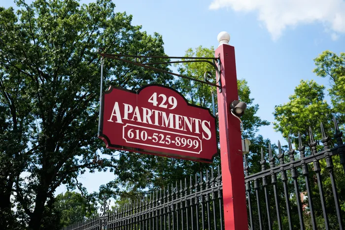 Charming 429 Apartments sign set against lush greenery and a clear blue sky, offering welcoming residential appeal.