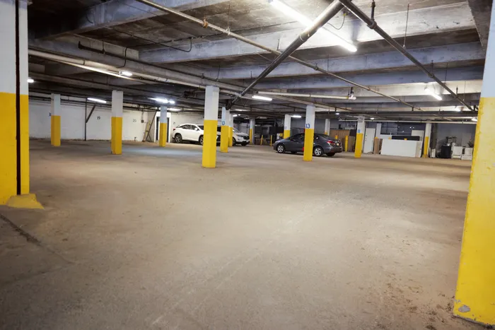 Spacious underground parking garage with ample lighting and multiple parking spaces available.