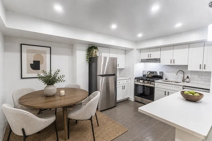Modern kitchen and dining area with sleek stainless steel appliances, stylish round wooden table, and elegant neutral decor.