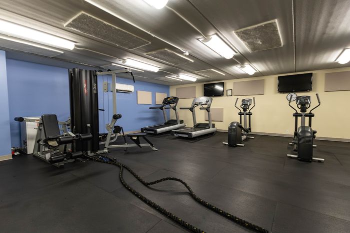 Modern fitness center with state-of-the-art equipment, including treadmills, ellipticals, and strength machines, under bright lighting.