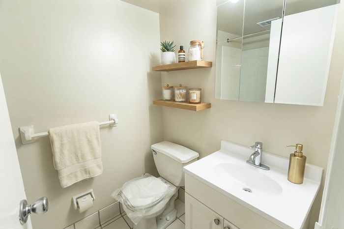 Modern bathroom with sleek white vanity, wall-mounted shelves, and elegant decor.