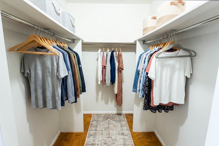 Spacious walk-in closet with organized shelving and elegant clothing display on wooden hangers, featuring a sophisticated area rug.