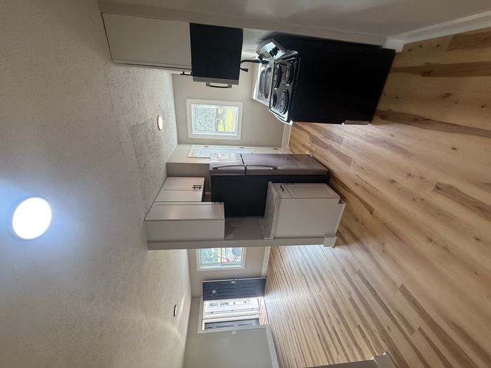 Bright and modern kitchen with sleek cabinets and stainless steel appliances, opening to a spacious living area with elegant wood flooring and abundant natural light.