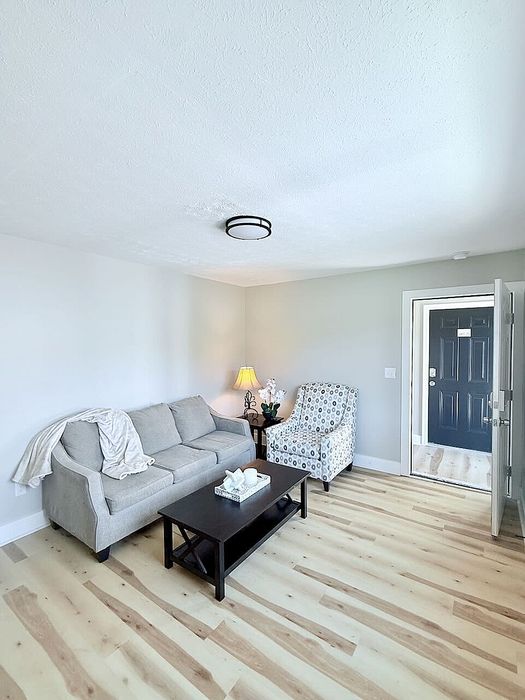 Inviting living room with modern gray sofa, stylish patterned armchair, and chic coffee table on elegant wood flooring.