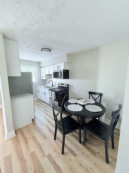 Charming kitchen dining area with modern black table set, sleek appliances, and bright natural light.