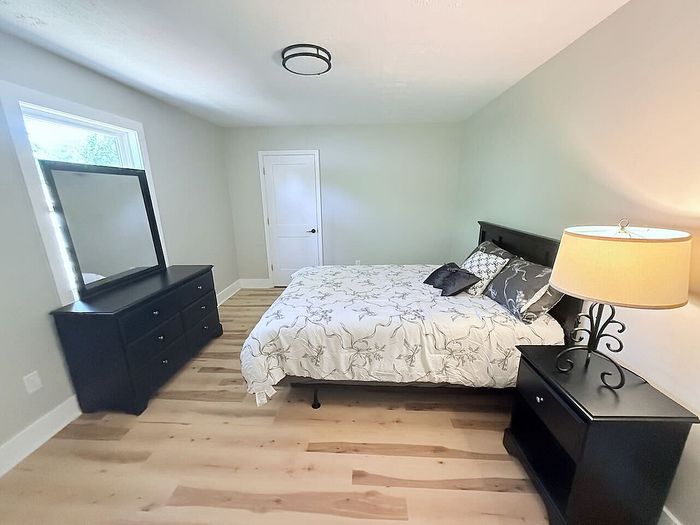 Bright and inviting bedroom with elegant decor, featuring a plush bed, modern dresser, and ambient lighting.