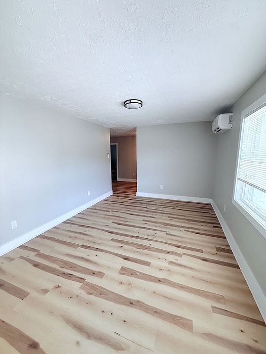 Bright and spacious room featuring sleek wood flooring and modern lighting, perfect for a cozy living area.