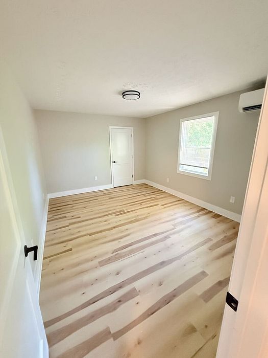 Bright and airy room with sleek hardwood floors, modern light fixture, and large window offering natural light.