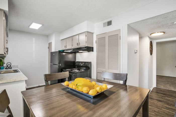 Modern kitchen with sleek appliances, elegant cabinetry, and a cozy dining table with vibrant fruit centerpiece.