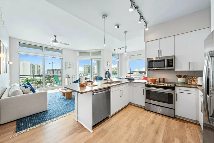 A spacious open-concept kitchen and living area in The DeSOTA, featuring a kitchen island, modern appliances, and a beautiful city view.