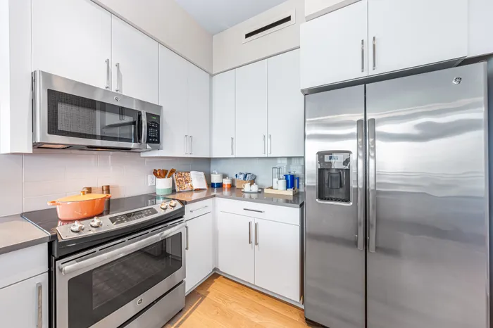 A modern kitchen in a Sarasota, FL apartment, with white cabinetry, stainless steel appliances, and sleek gray countertops.