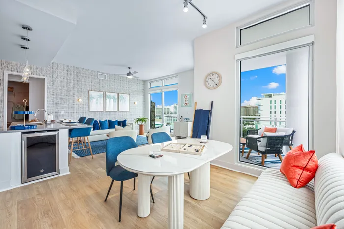 An open-concept living space in a Sarasota, FL apartment, with a dining area, a modern kitchen with a wine cooler, and a balcony.