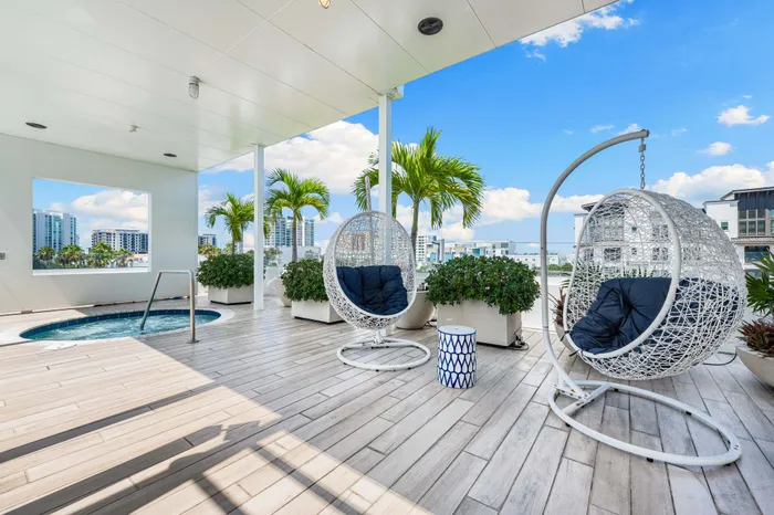 An outdoor lounge area at downtown Sarasota, FL with unique, modern hanging chairs, a hot tub, and a view of the city.