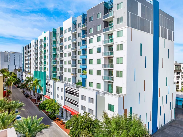 The exterior of The DeSOTA, a modern multi-story building with a distinctive white, gray, and blue facade, located in a downtown area.