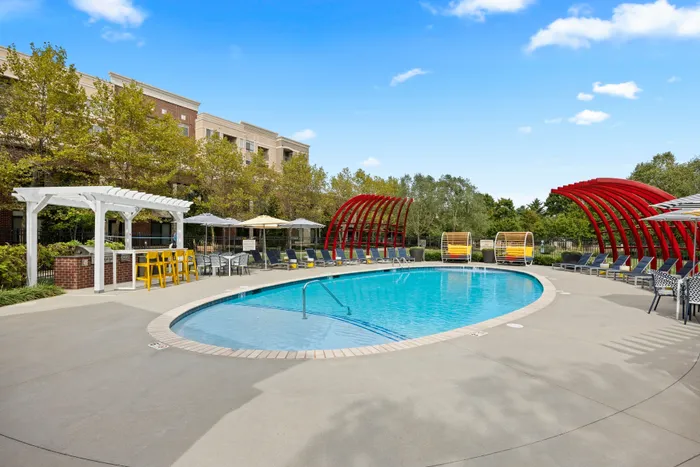 Luxurious apartment pool with modern seating and vibrant red accents