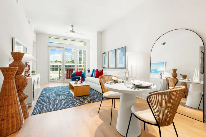 An open-concept living and dining area in a The DeSOTA apartment, with a large arched mirror, a dining table, and a sofa.
