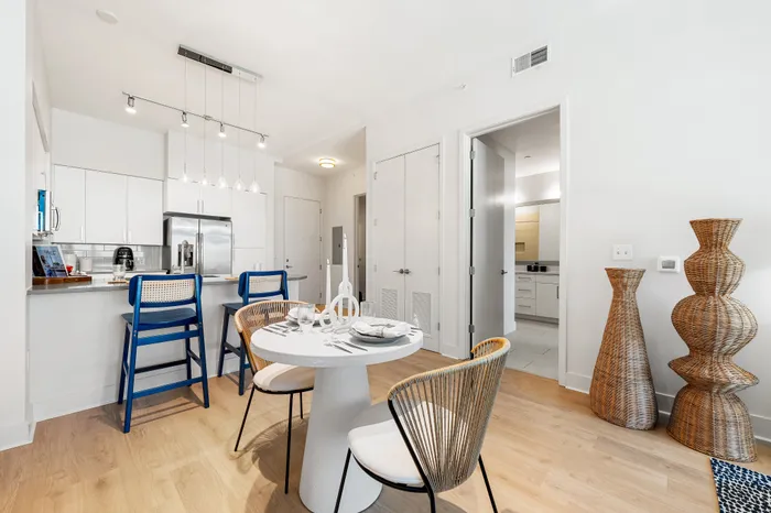 An open-concept living space in a The DeSOTA apartment, showing a dining area, a kitchen with an island, and unique woven decor.
