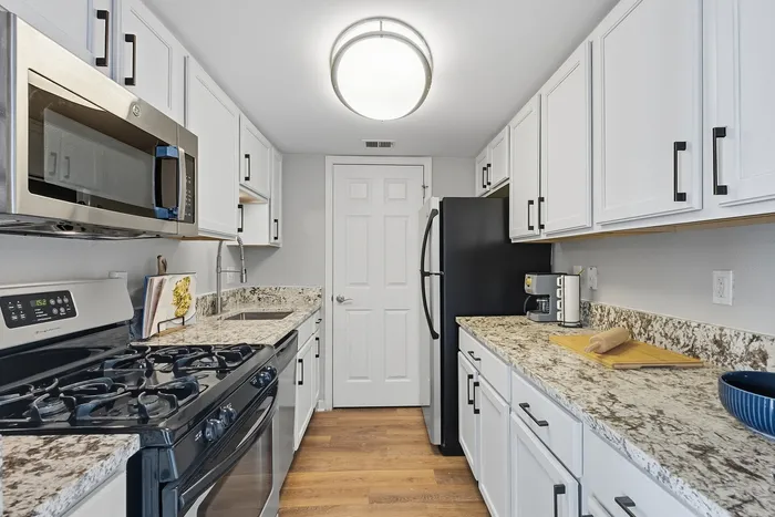 Modern kitchen with sleek granite countertops, stainless steel appliances, and crisp white cabinetry, perfect for culinary enthusiasts.
