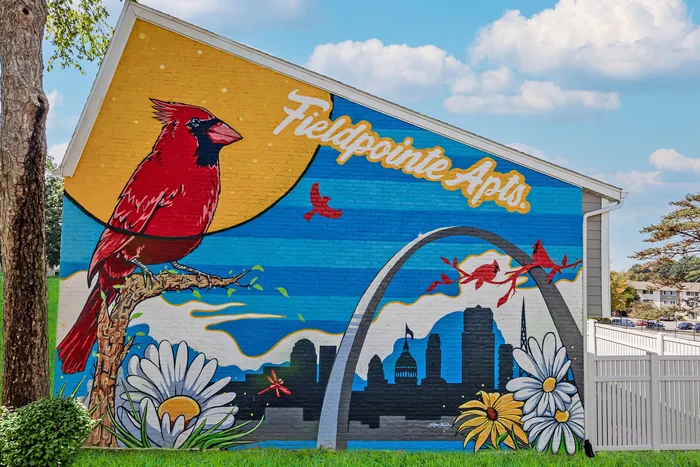 Vibrant mural at Fieldpointe Apartments featuring a red cardinal, St. Louis skyline, and colorful flowers, capturing a lively and artistic community atmosphere.