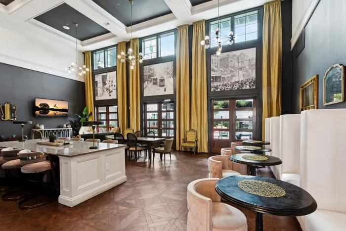 Luxurious lounge with high ceilings, elegant chandeliers, and plush seating, featuring stylish decor and large windows with velvet drapes.