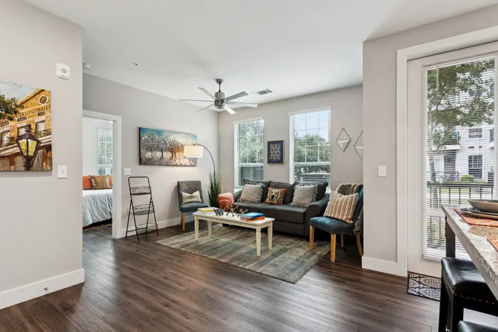 Inviting living room with modern decor, featuring a cozy sofa, elegant chairs, and abundant natural light from large windows.
