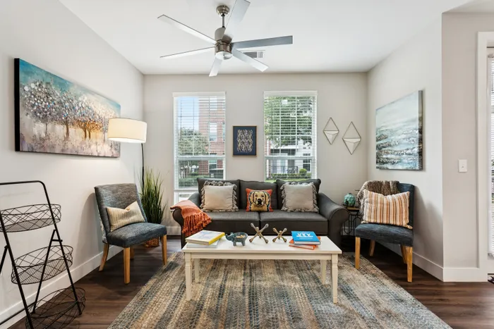 Chic and cozy living room with modern furniture, vibrant artwork, and abundant natural light from large windows.