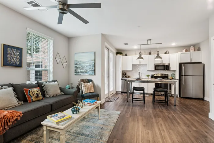 Modern open-plan living room and kitchen with stylish decor, featuring a cozy sofa and sleek stainless steel appliances.