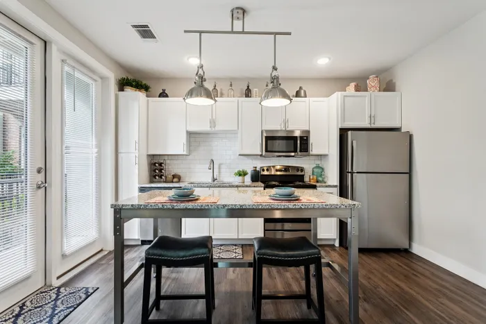 Chic modern kitchen with sleek stainless steel appliances, elegant lighting, and a stylish breakfast bar in an inviting open space.