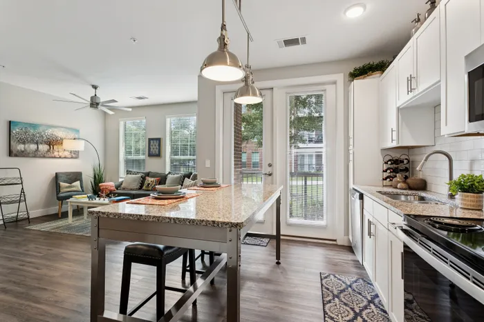 Chic open-concept kitchen and living area with elegant granite countertops, cozy seating, and abundant natural light through large windows.