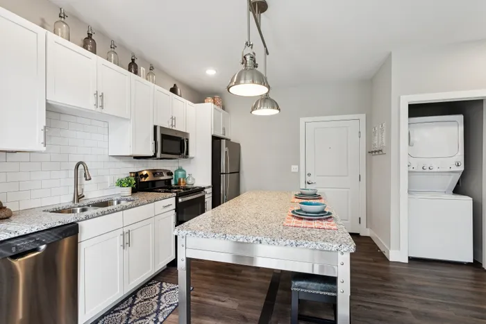 Modern kitchen with sleek granite countertops, stainless steel appliances, and cozy dining area, complemented by a convenient in-unit washer and dryer.