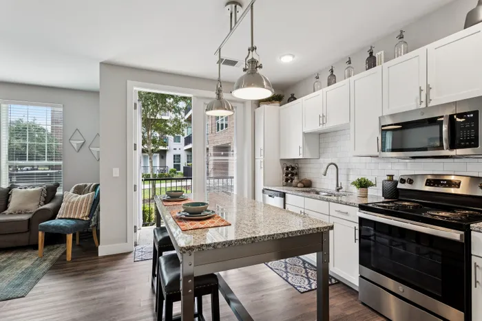 Modern kitchen with elegant granite countertops, stainless steel appliances, and bright open layout leading to a cozy living space.