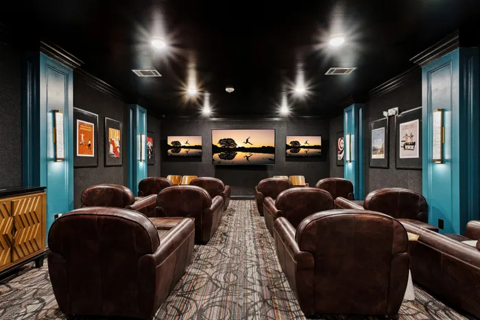 Luxurious private cinema room with plush leather seating, modern decor, and ambient lighting for a premium viewing experience.