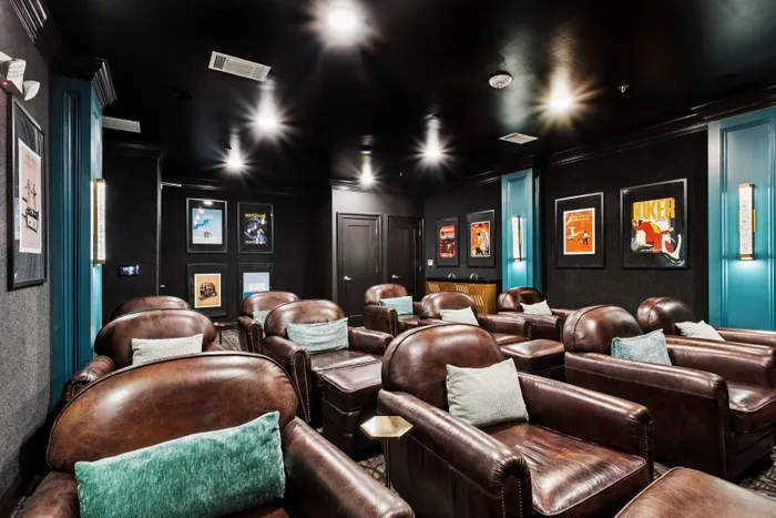 Luxurious home theater room with plush leather seating, ambient lighting, and stylish movie posters for an ultimate cinematic experience.