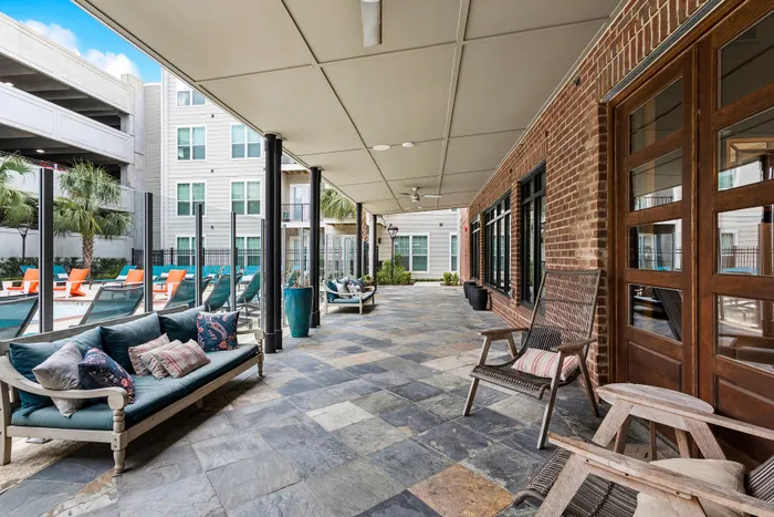 Chic outdoor lounge area with modern seating, poolside views, and lush palm trees for a relaxing ambiance.