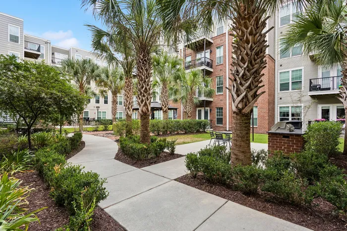 Inviting apartment complex courtyard featuring lush palm trees, well-maintained landscaping, and outdoor seating area for relaxation.