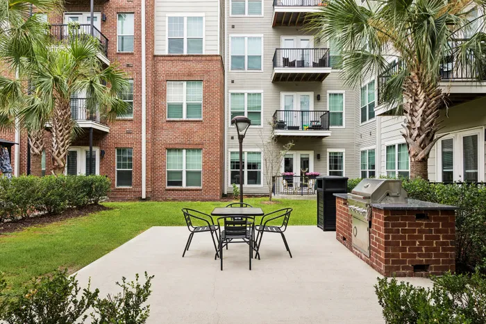Inviting apartment courtyard featuring well-maintained landscaping, outdoor seating, and a built-in grill area for communal relaxation and entertainment.