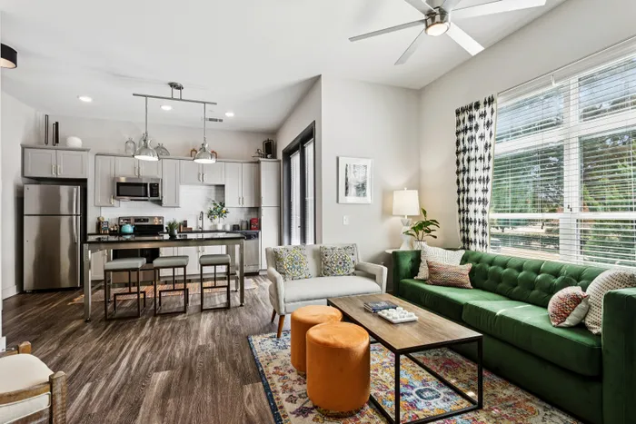 Contemporary open-concept living area with elegant kitchen, modern appliances, and cozy seating arrangement featuring a plush green sofa.